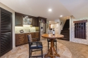 Dark cabinets contrast the floors, walls, and ceiling, while the stone backsplash and wall add sophistication. The shuttered door hides the sump pump room and matches other window coverings.