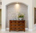  We made this entry hall area a dramatic focal point by adding the patterned grey silk upholstered wall treatment. It was previously white and blended in to the rest of the entry hall.