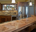 The bar area was done to reflect the male client's love of hunting. The stone backsplash gives it a rustic feel, and the superb, custom-made herringbone wood bar top is the cherry on top.